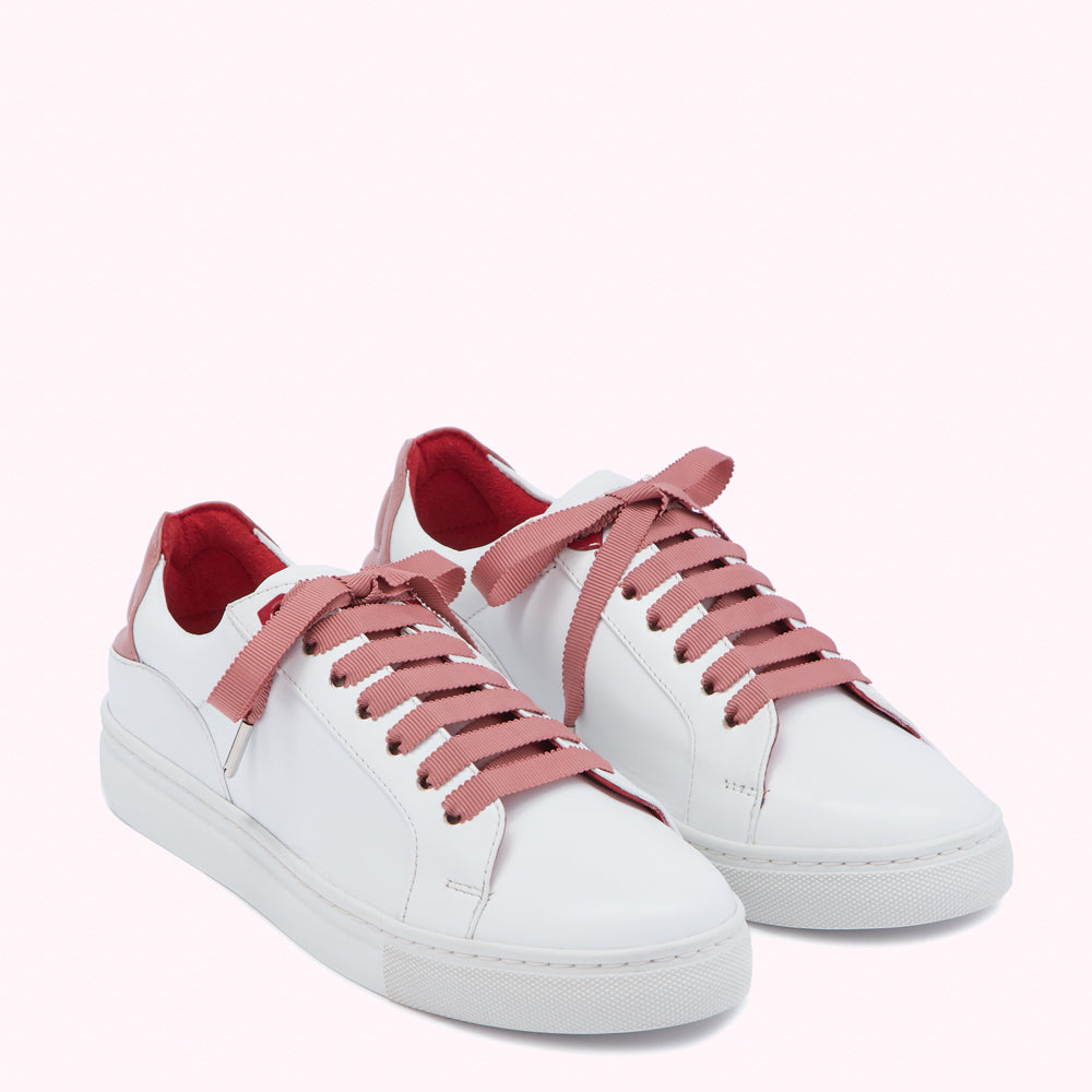 Pair of white leather sneakers with dusty rose laces and red heel lining, on a white background.
