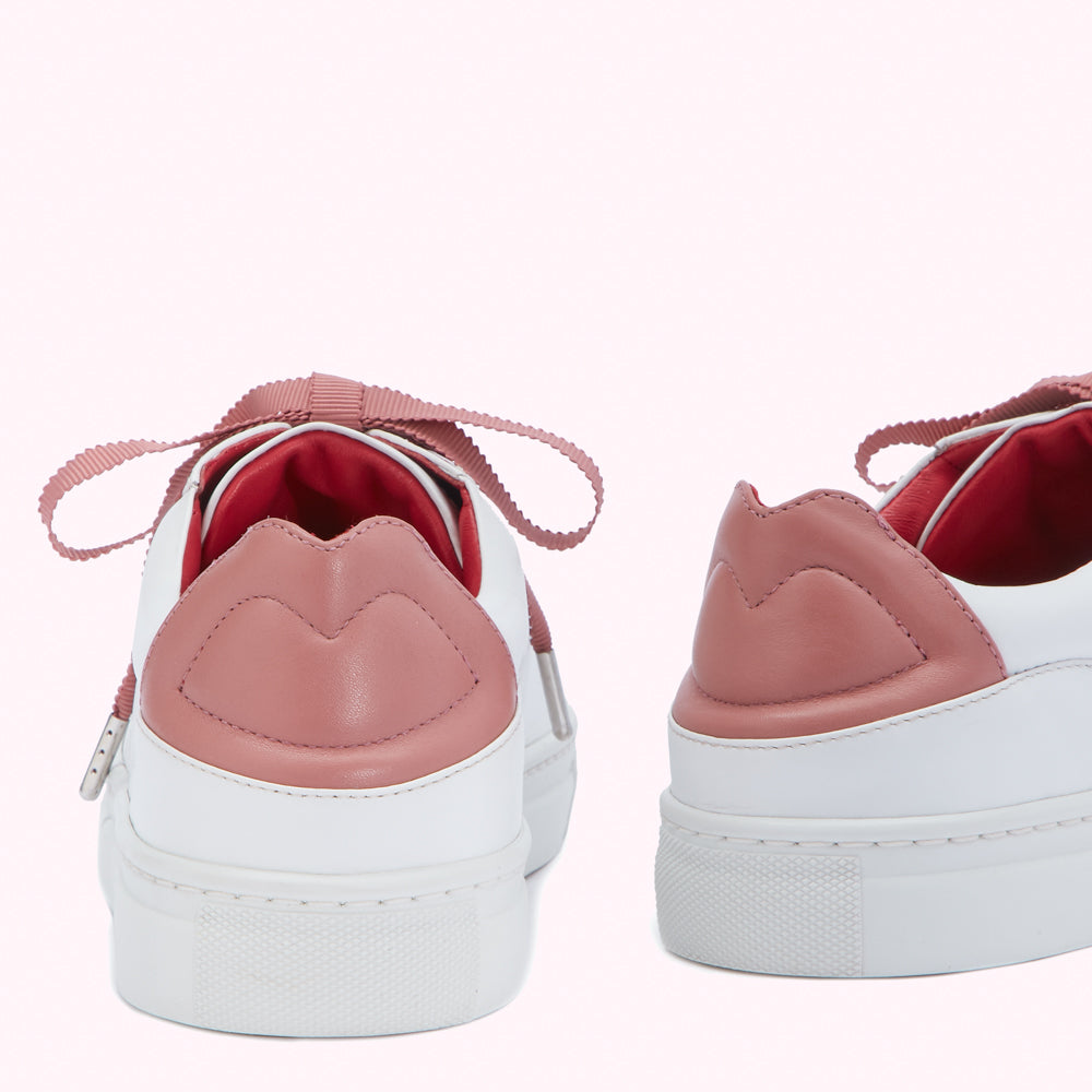 Rear view of a pair of white leather sneakers with rose-pink accents and grosgrain ribbon laces against a white background.