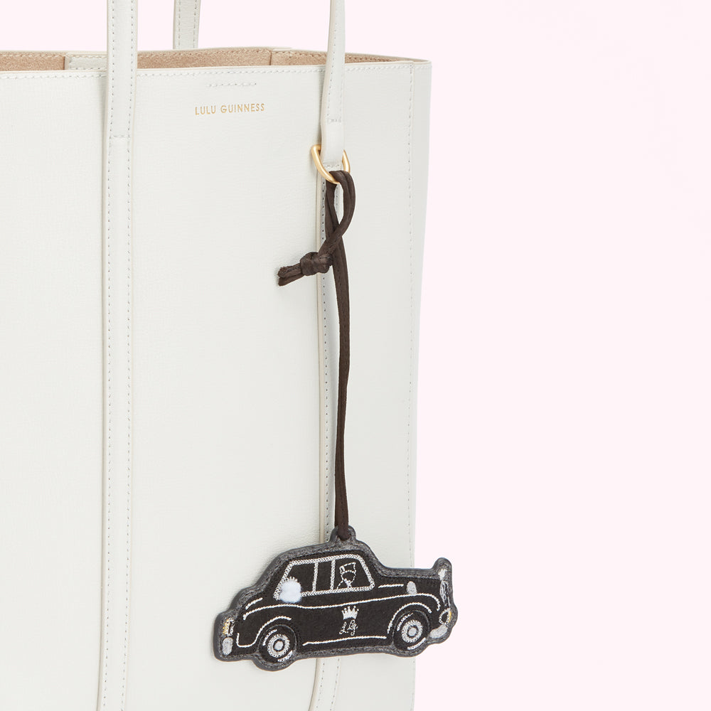 Off-white leather tote bag with a dark brown leather tag shaped like a London taxi cab.