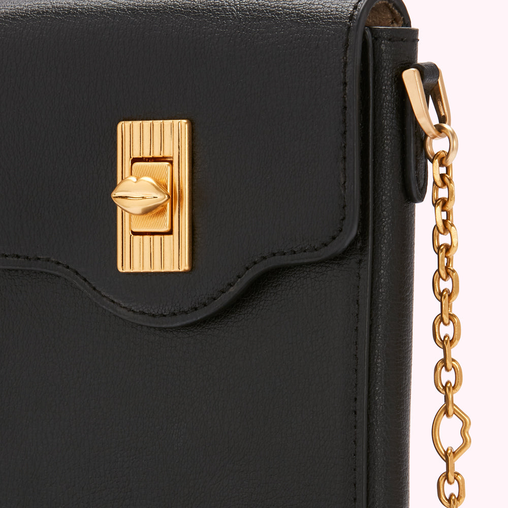 Close-up of a black leather purse with a gold lip-shaped clasp and gold chain strap.
