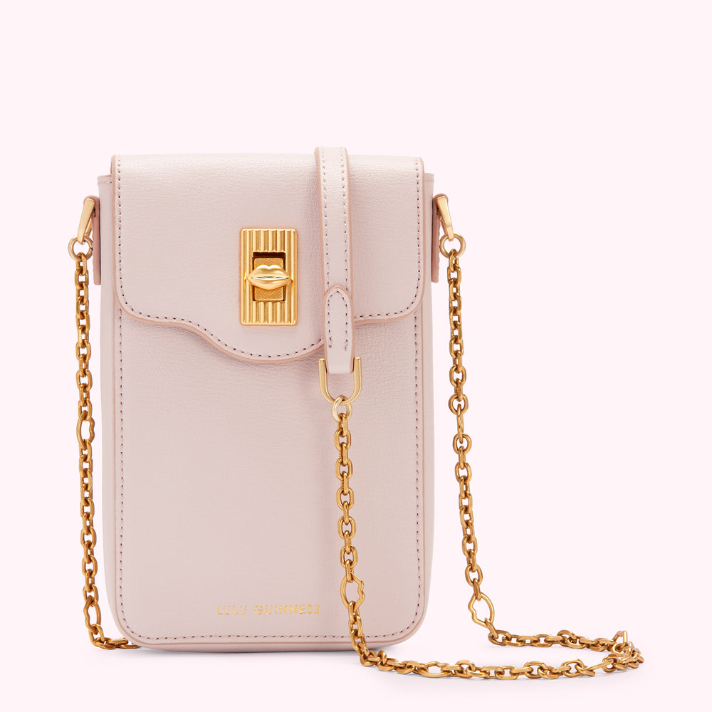 A pale pink Lulu Guinness crossbody bag with a gold chain strap and a signature lip-shaped clasp.

