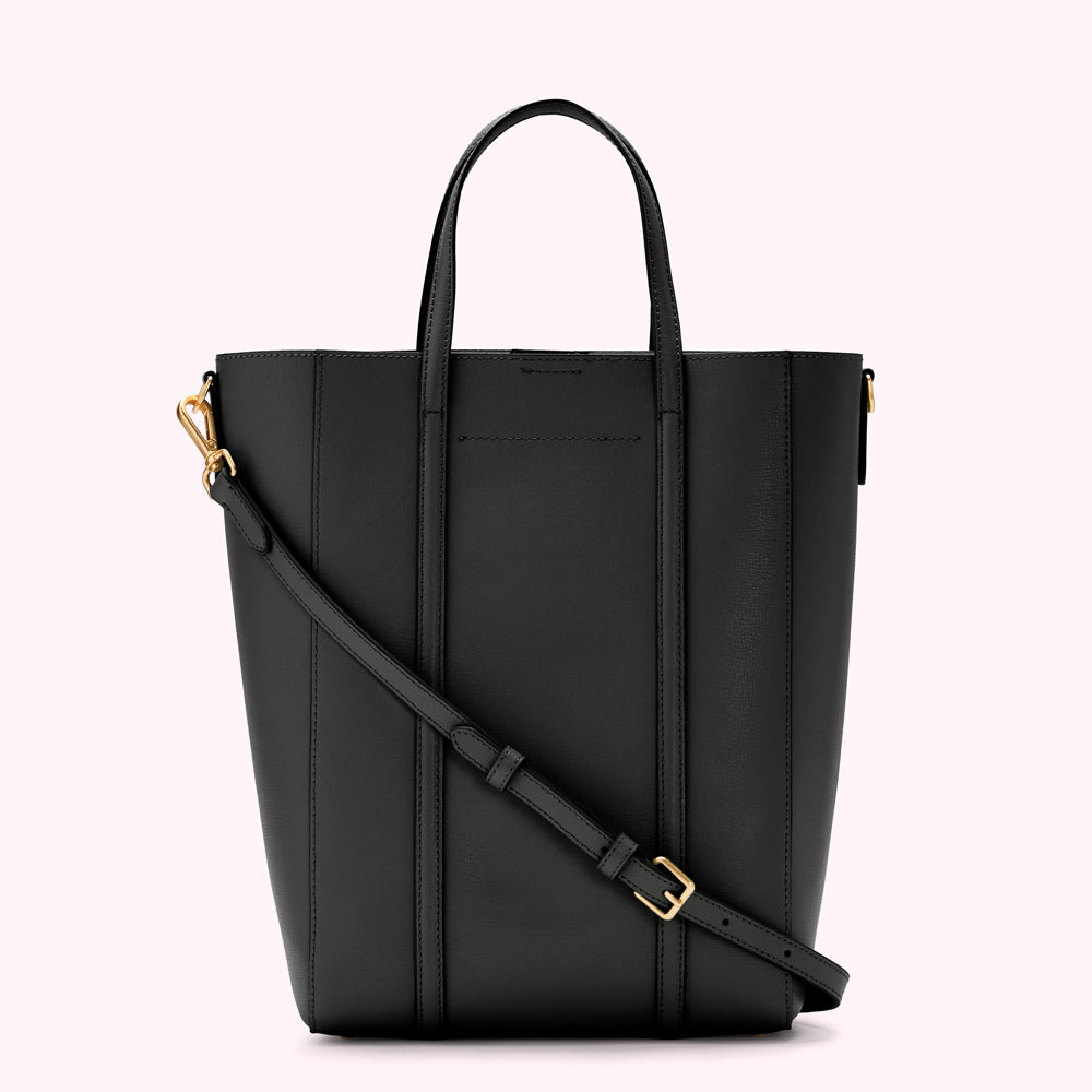 Black leather tote bag with gold-toned hardware and an adjustable shoulder strap against a white background.
