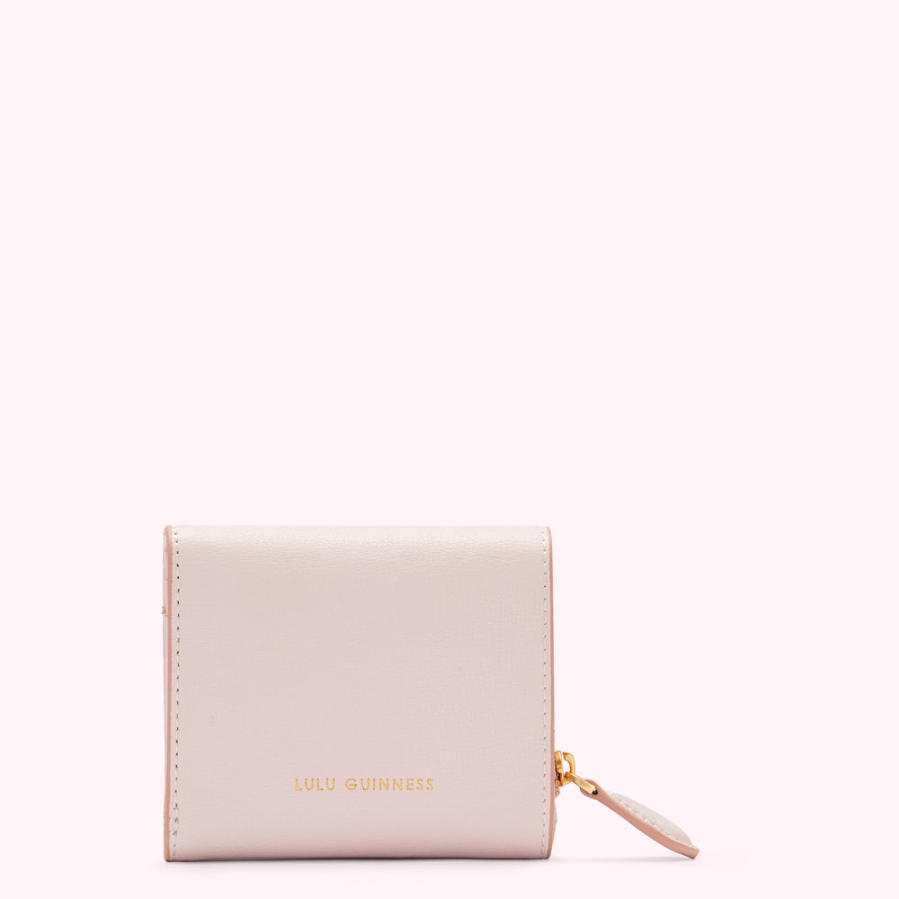 A pale pink Lulu Guinness zip-around wallet against a white background.

