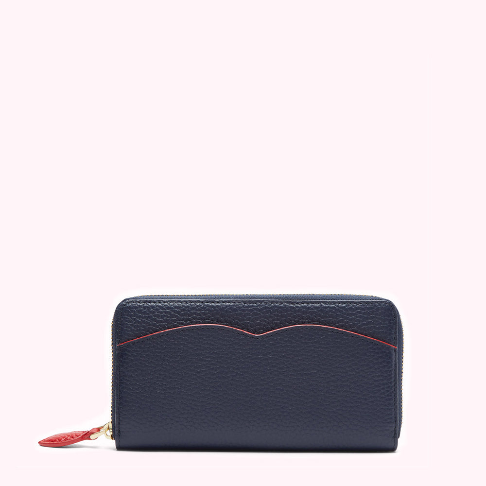 Navy blue leather zip-around wallet with red detailing against a white background.
