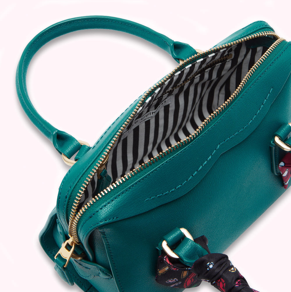 Teal leather handbag with gold hardware and black and white striped lining, partially unzipped to show interior. A colorful scarf is tied to one of the handles.
