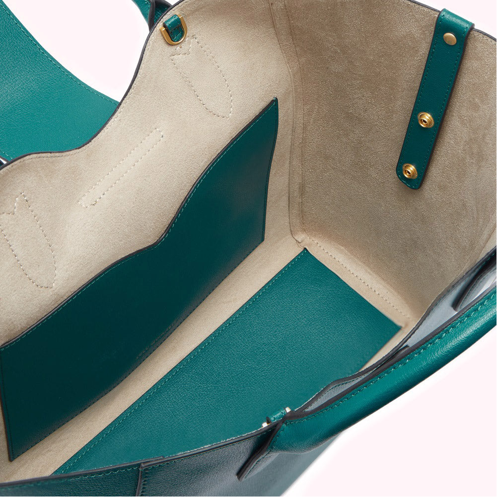 Interior view of a teal leather tote bag with beige suede lining and gold-toned hardware.
