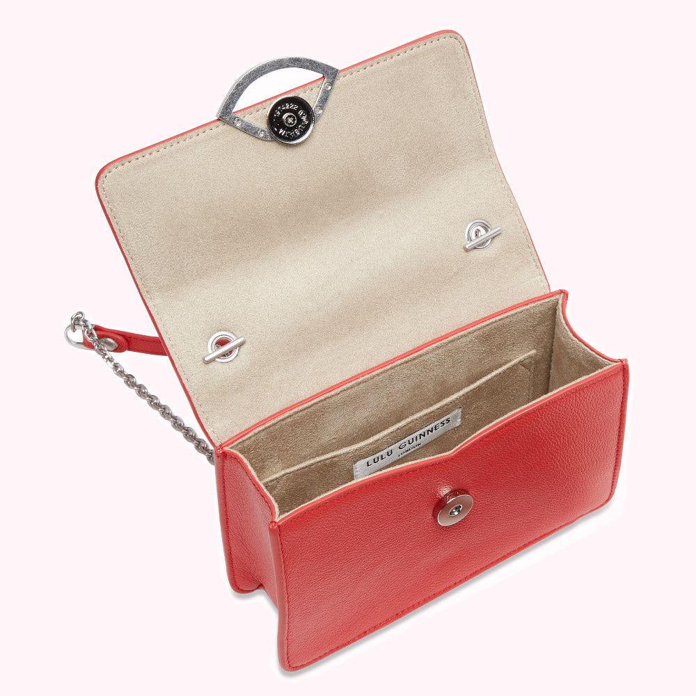 Red Lulu Guinness crossbody bag with silver-toned hardware and a beige interior, shown open.
