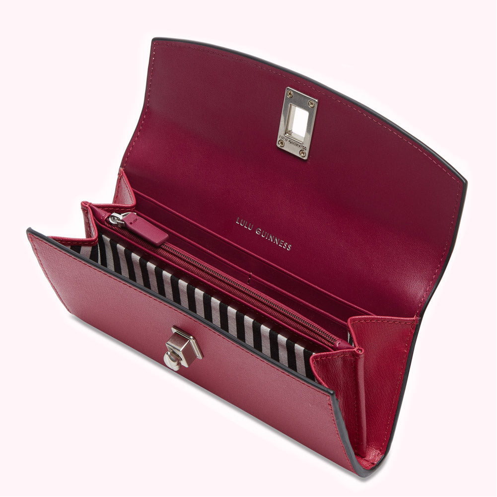Open red Lulu Guinness wallet with black and white striped interior.
