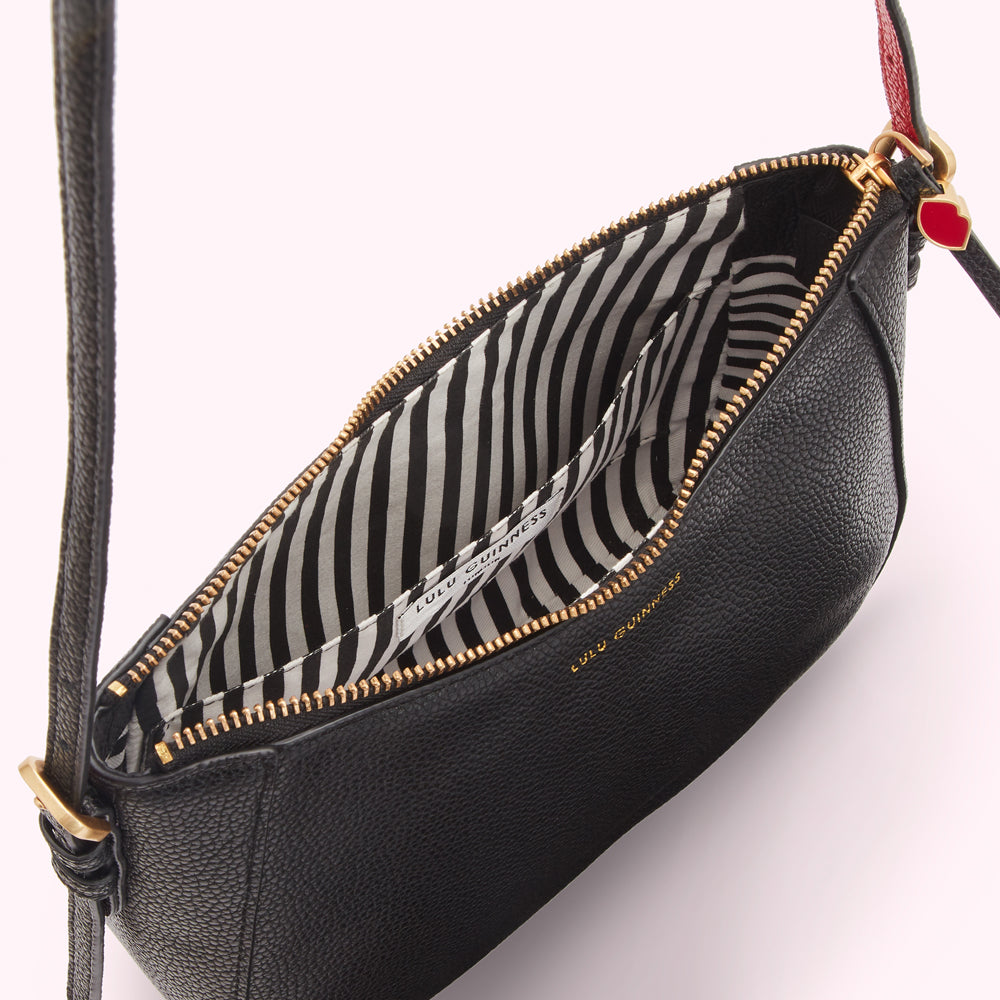 Open black Lulu Guinness crossbody bag with black and white striped interior.