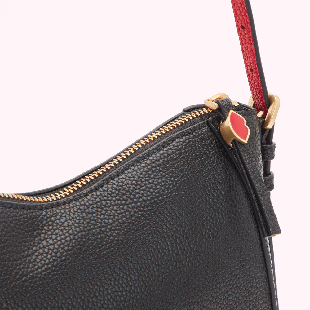 Close-up of a black leather Kate Spade handbag with gold zipper and red and gold detail.