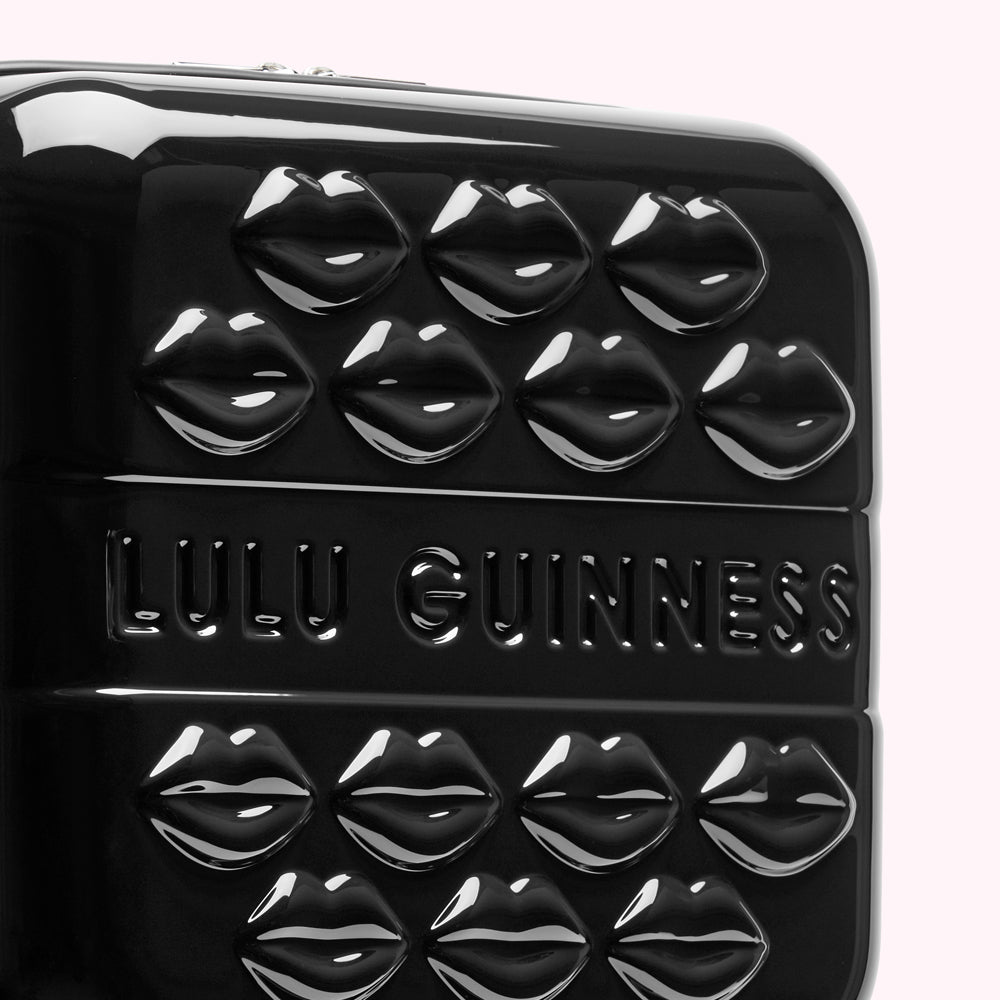 Close-up of a black Lulu Guinness suitcase decorated with embossed lips.