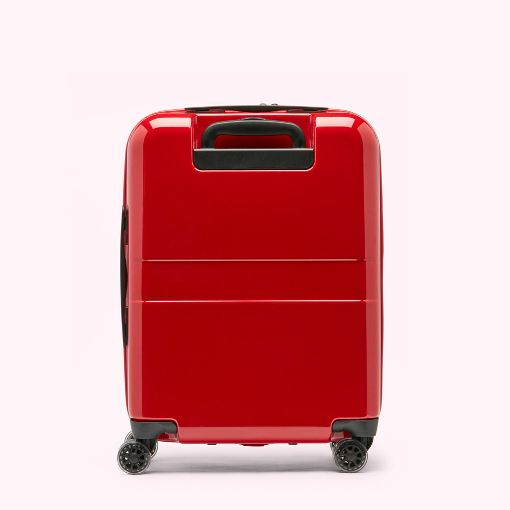 Red carry-on suitcase with black handle and wheels against a white background.
