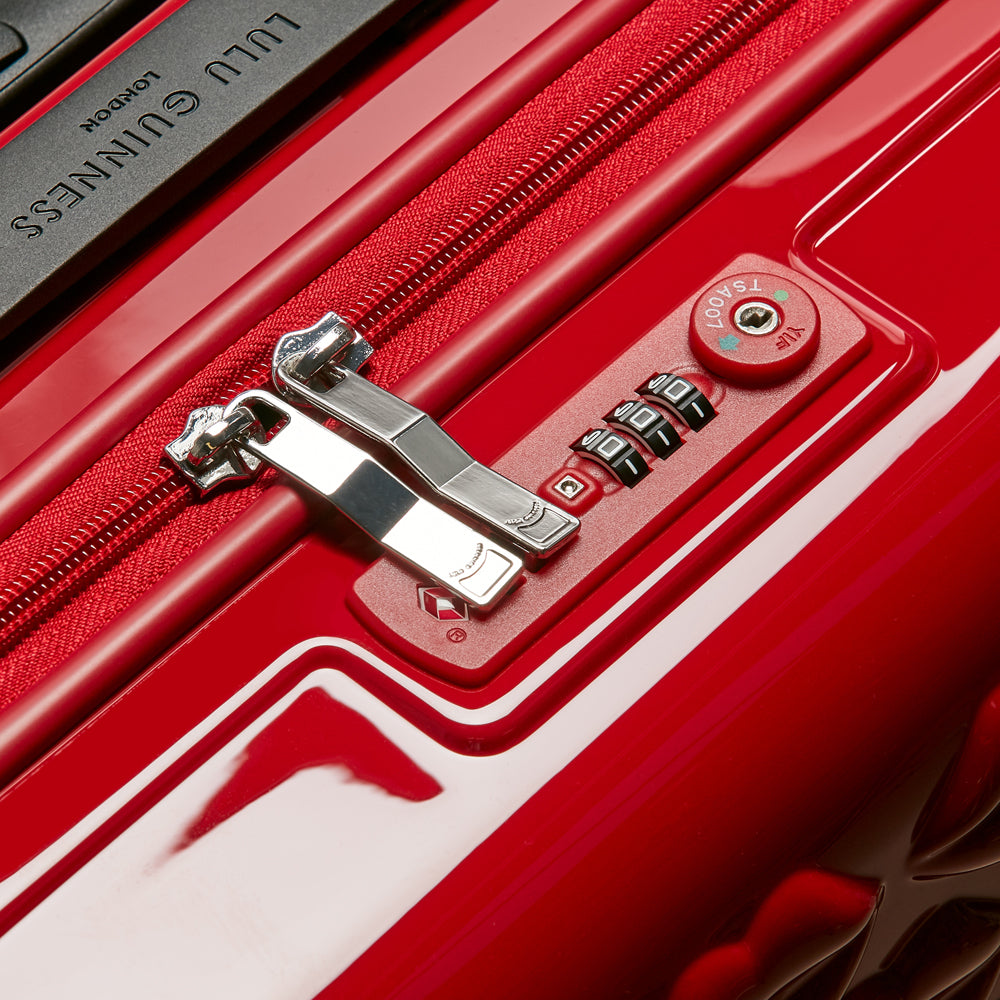 Close-up of a red Lulu Guinness suitcase showing the TSA-approved combination lock and zipper.

