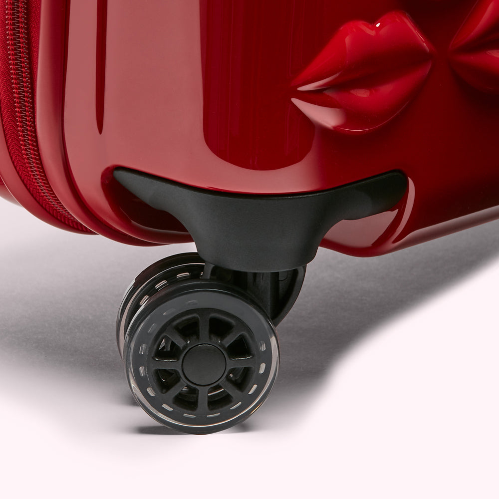 Close-up of a red suitcase wheel with a lip design on the suitcase.
