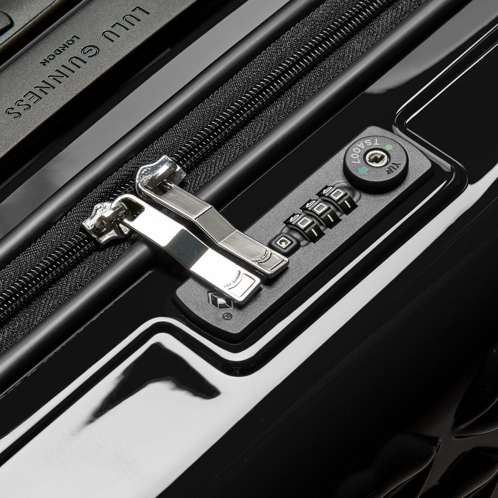 Close-up of a black suitcase's TSA-approved combination lock and zipper.
