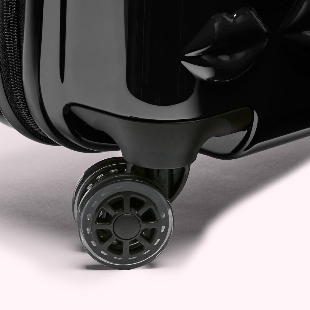Close-up of a black suitcase wheel against a white background.
