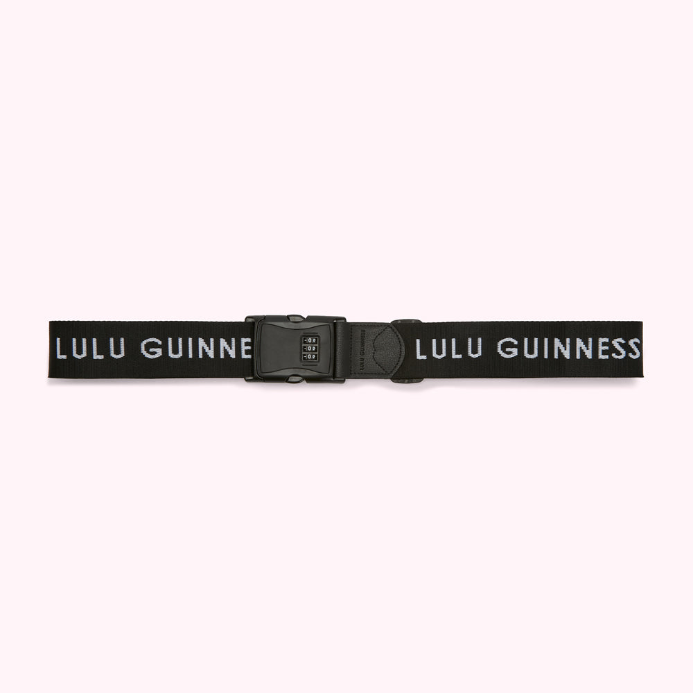 Black luggage strap with a combination lock and the text "Lulu Guinness" printed in white.