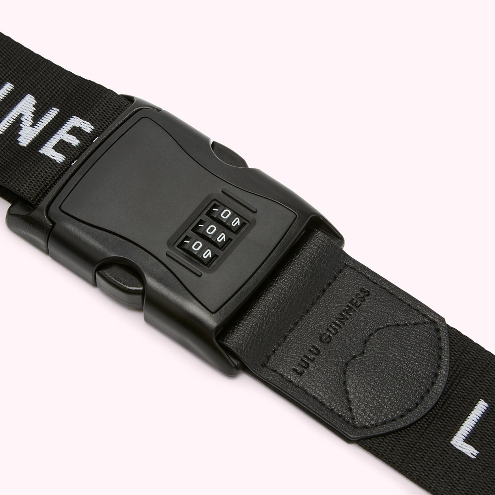Close-up of a black luggage strap with a built-in combination lock. The strap features the "Lulu Guinness" branding.