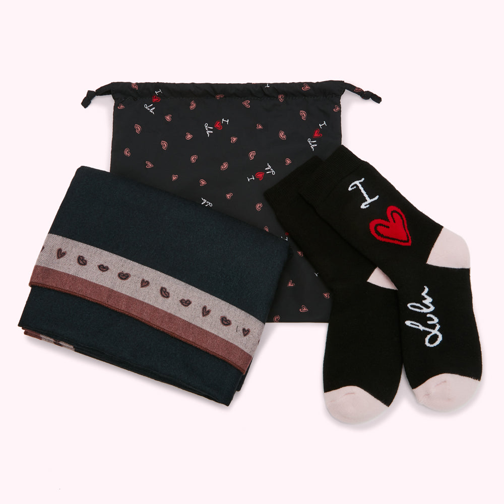 Dark teal scarf with a mauve band of hearts and lips, black socks with "I love Lulu" written on them, and a black gift bag with a repeating pattern of hearts and lips; all on a white background.