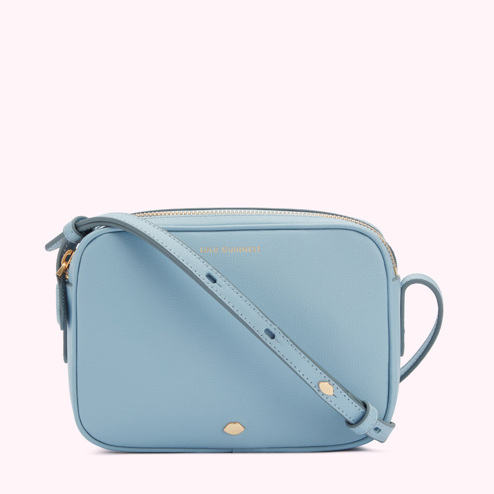 Light blue leather crossbody bag with gold hardware and the Isle Guernsey logo.
