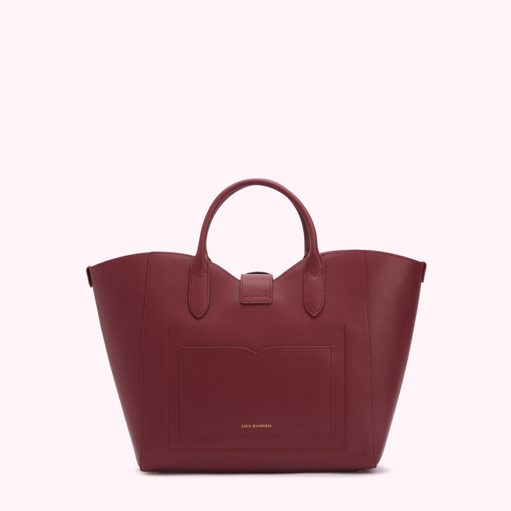 Burgundy Lulu Guinness tote bag with a front pocket, viewed from the back against a white background.
