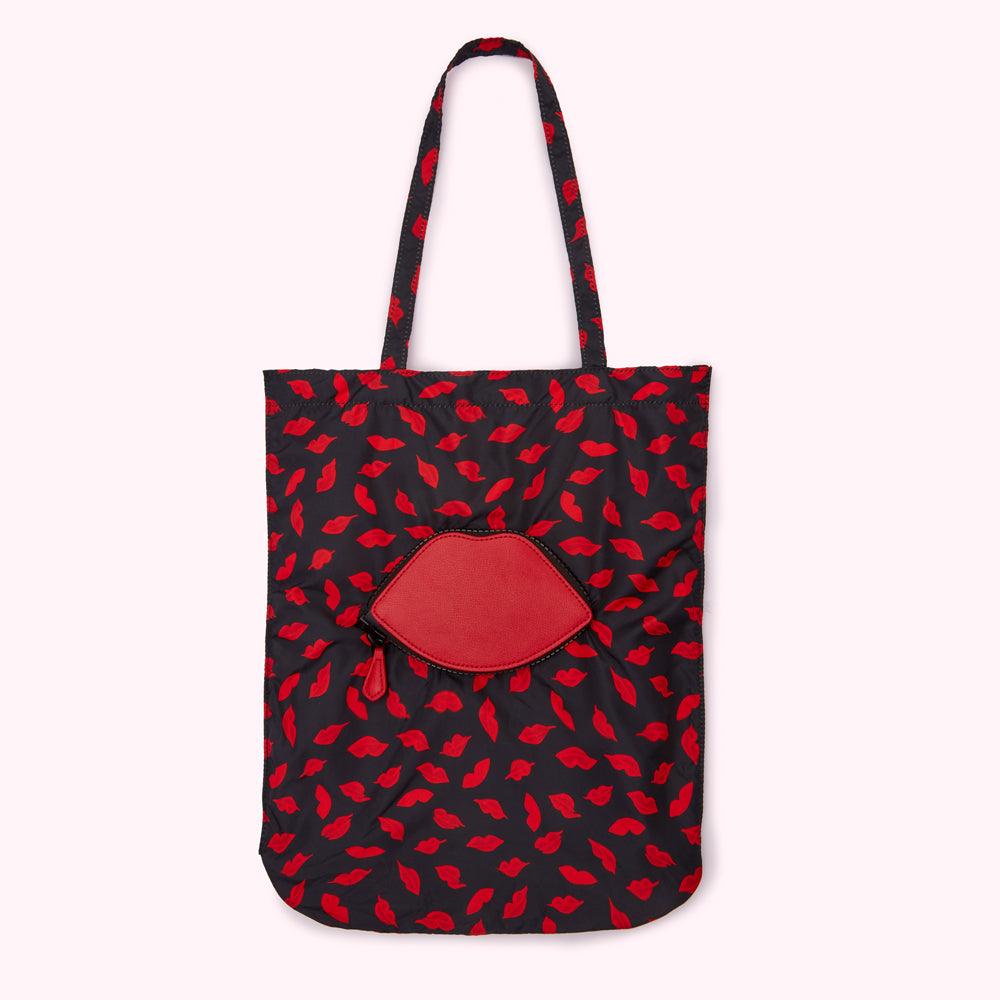 Black tote bag with a red lips pattern and a red lip-shaped pocket.
