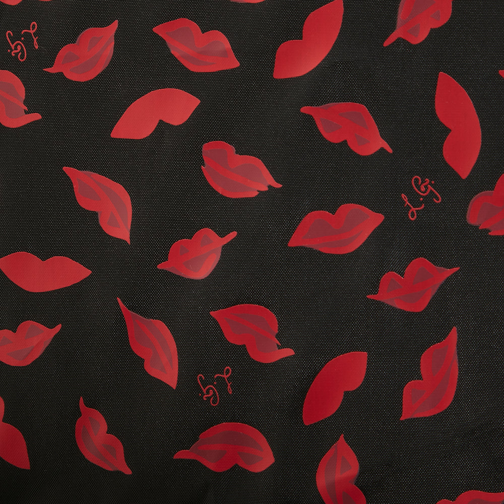 Close-up view of a black fabric with a repeating pattern of red lips.