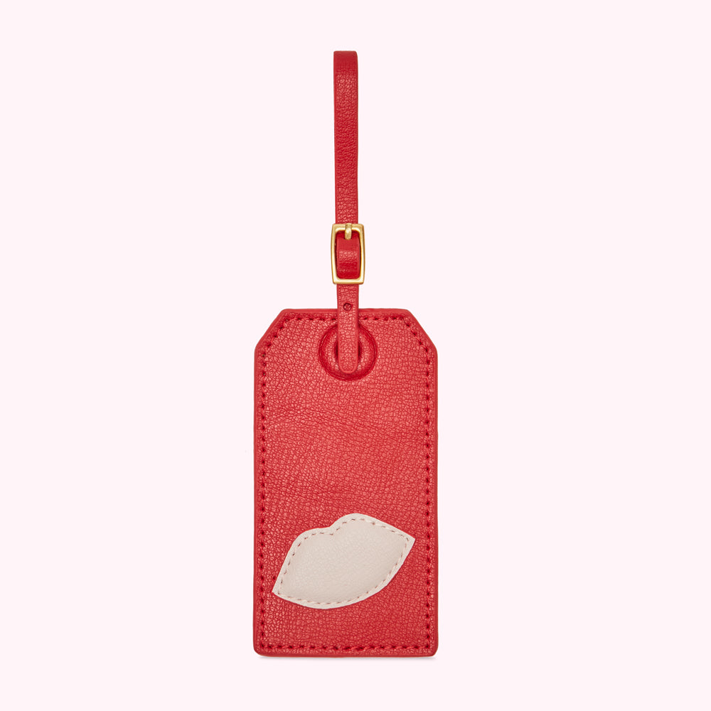 Red leather luggage tag with a white lip design.
