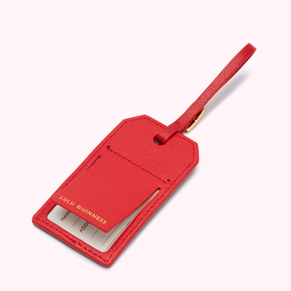 Red leather luggage tag with gold lettering and a flap to insert contact information.
