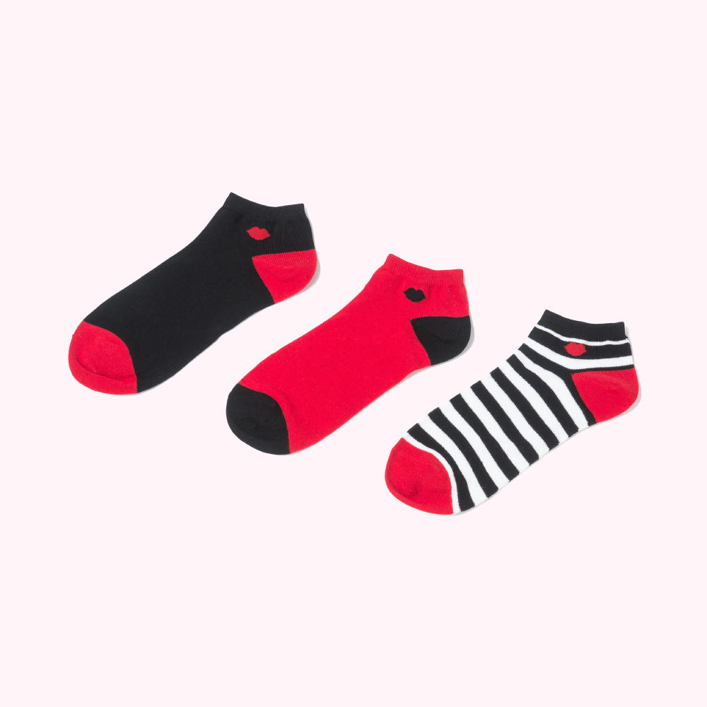 Three ankle socks; one black, one red, and one black and white striped; all with a small red lip design.
