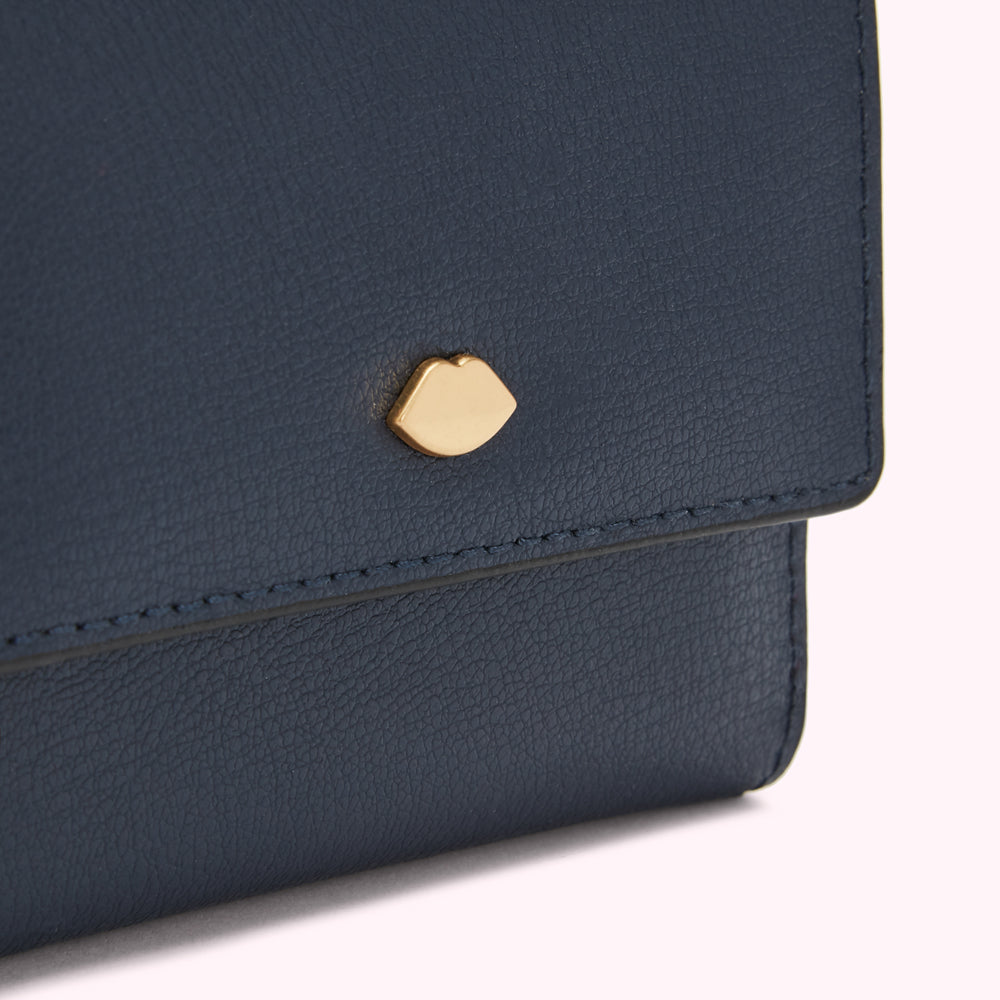 Close-up of a navy blue leather wallet with a gold lip-shaped emblem.
