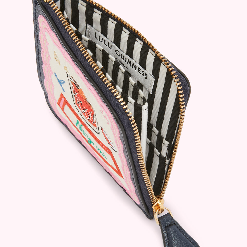 Open navy Lulu Guinness zip-around purse with a whimsical embroidered design and black and white striped interior.

