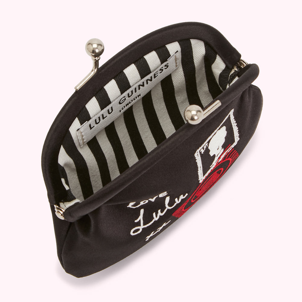 Black satin Lulu Guinness purse with black and white striped lining, featuring embroidered lettering and a red lip print.