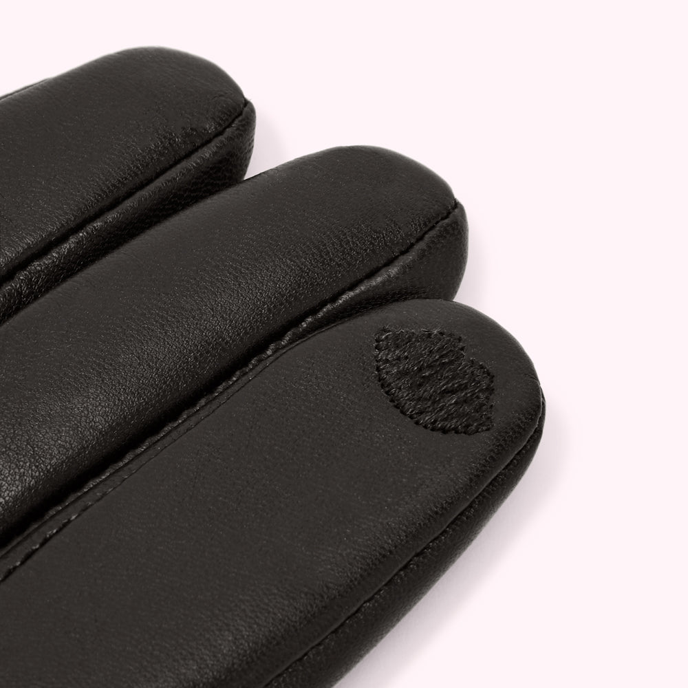 Close-up of black leather gloves with a small embroidered detail.
