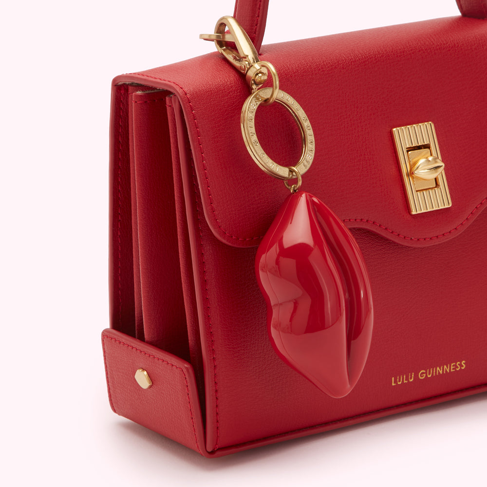 Close-up of a red Lulu Guinness handbag with a red lip-shaped keychain.