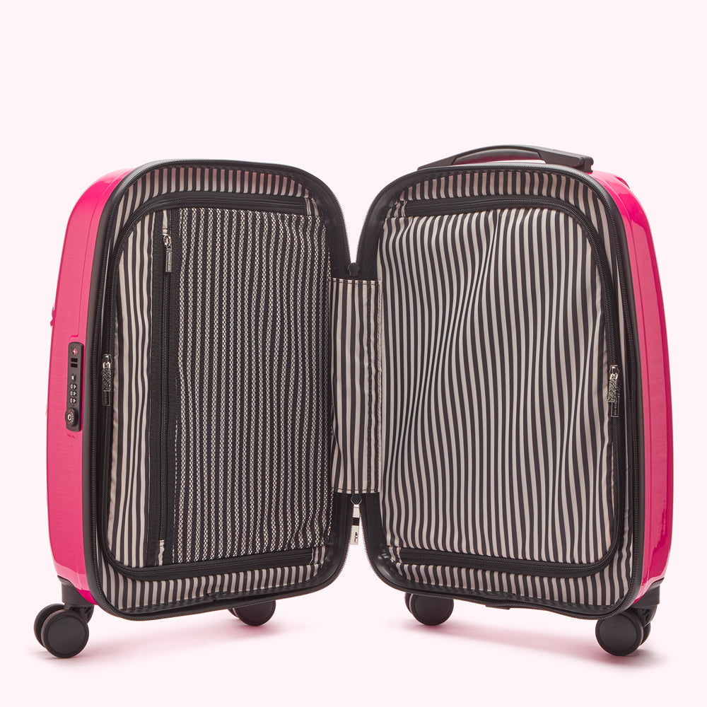 Pink suitcase open to reveal black and white striped interior lining.
