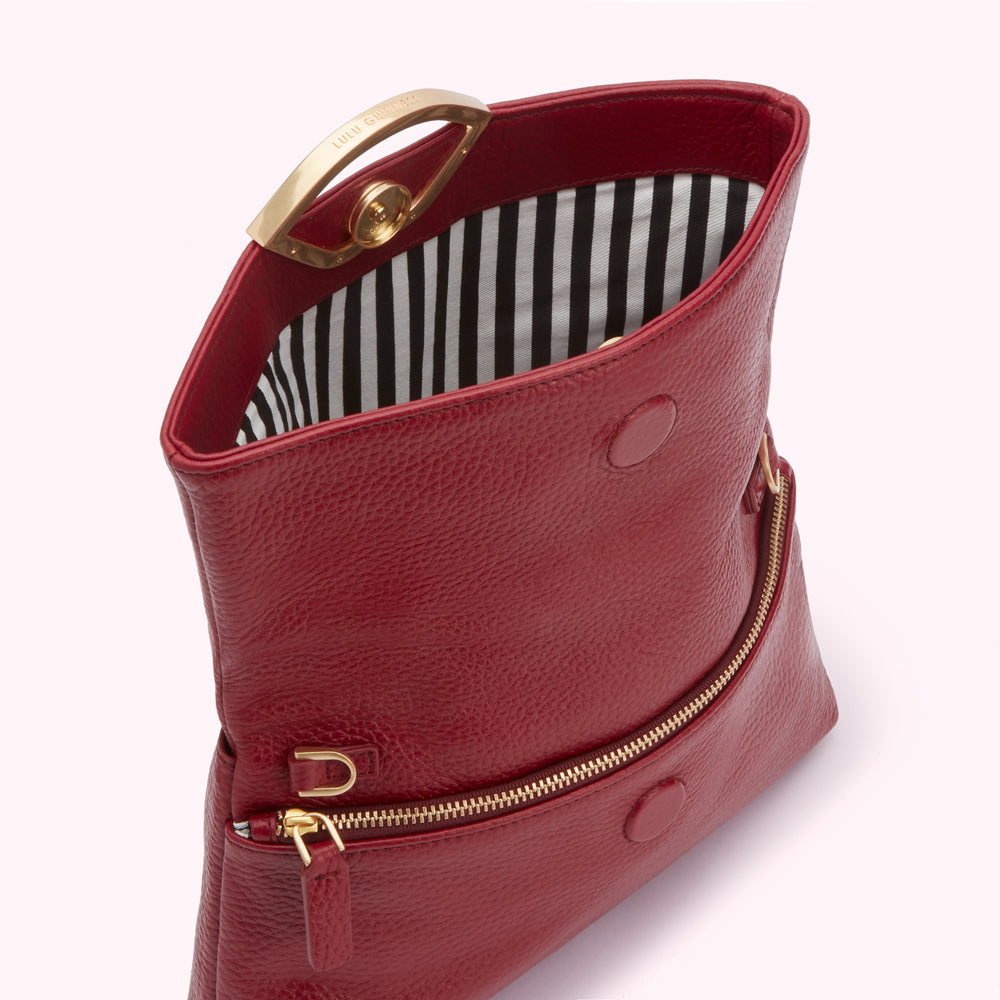 Red leather Lulu Guinness handbag open to reveal black and white striped interior.
