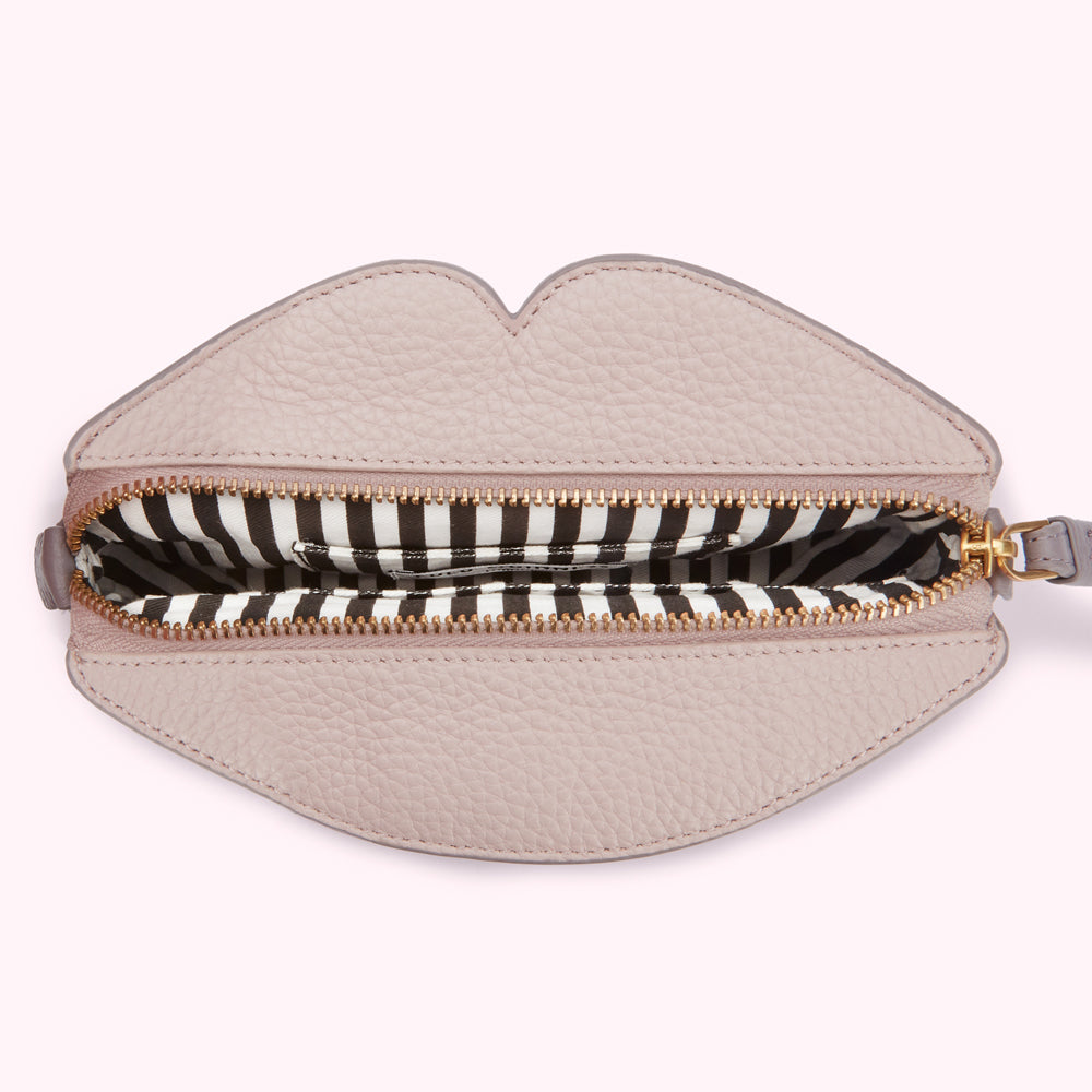 Pink lip-shaped purse open to reveal a black and white striped interior.
