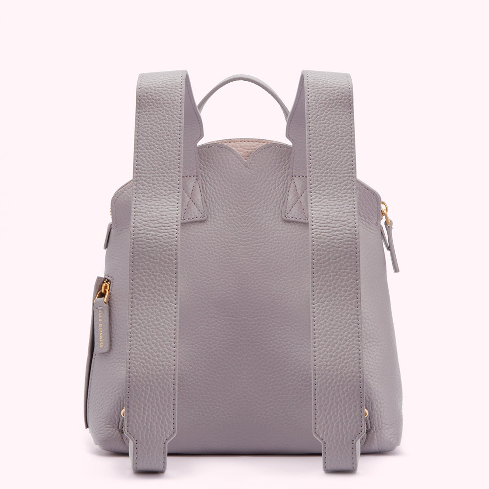 Rear view of a grey leather backpack with gold zippers.
