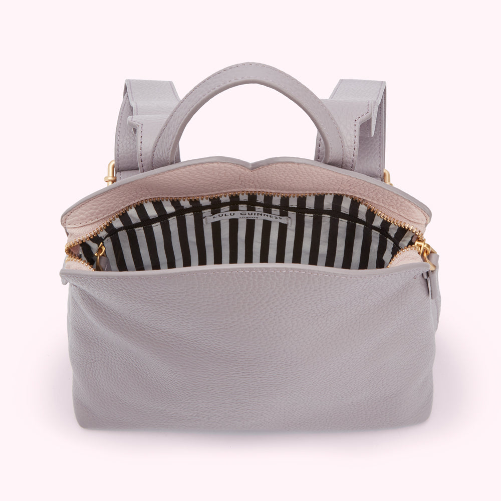 Lilac Lulu Guinness backpack open to reveal black and white striped interior.
