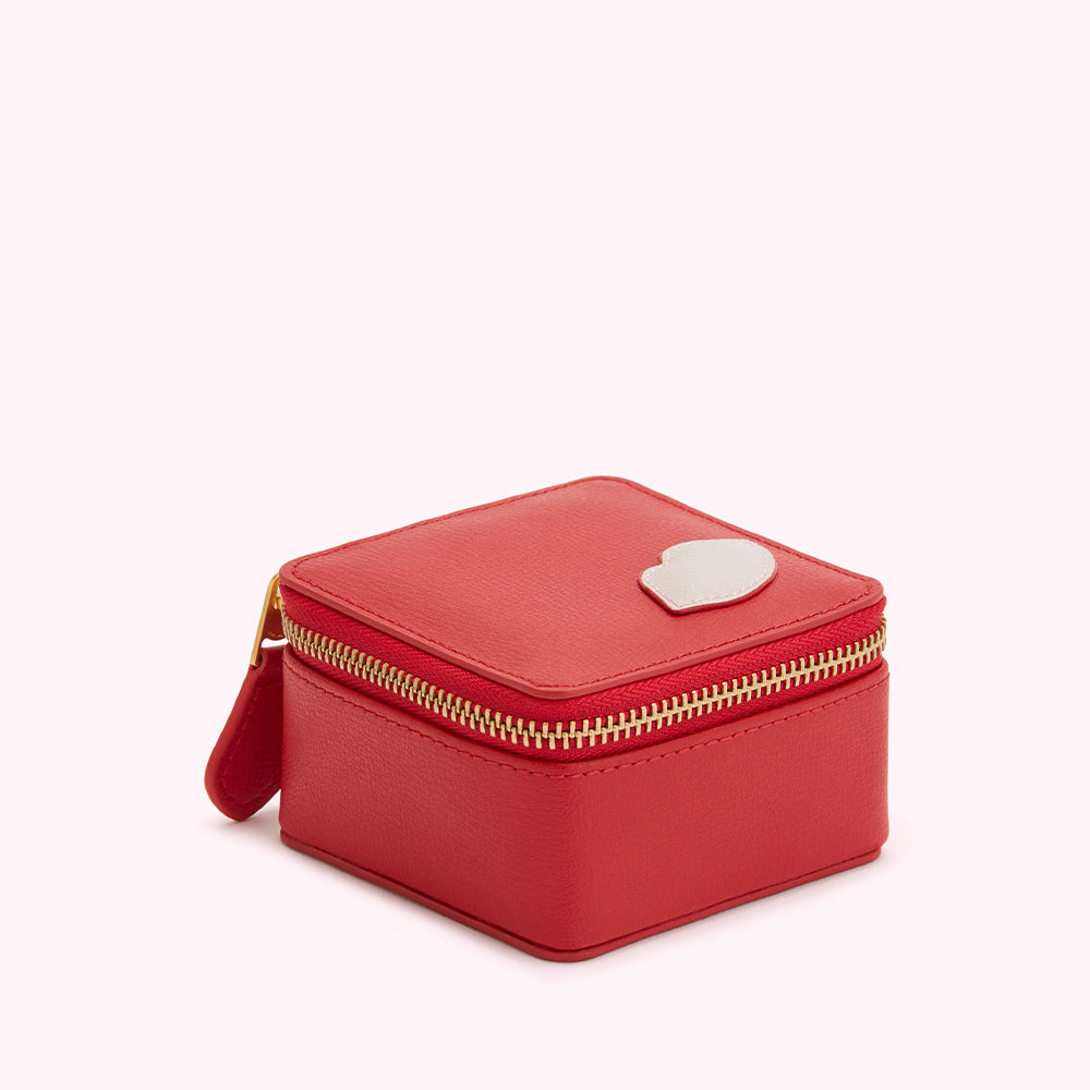 Red leather jewelry box with gold zipper and a small silver heart detail.
