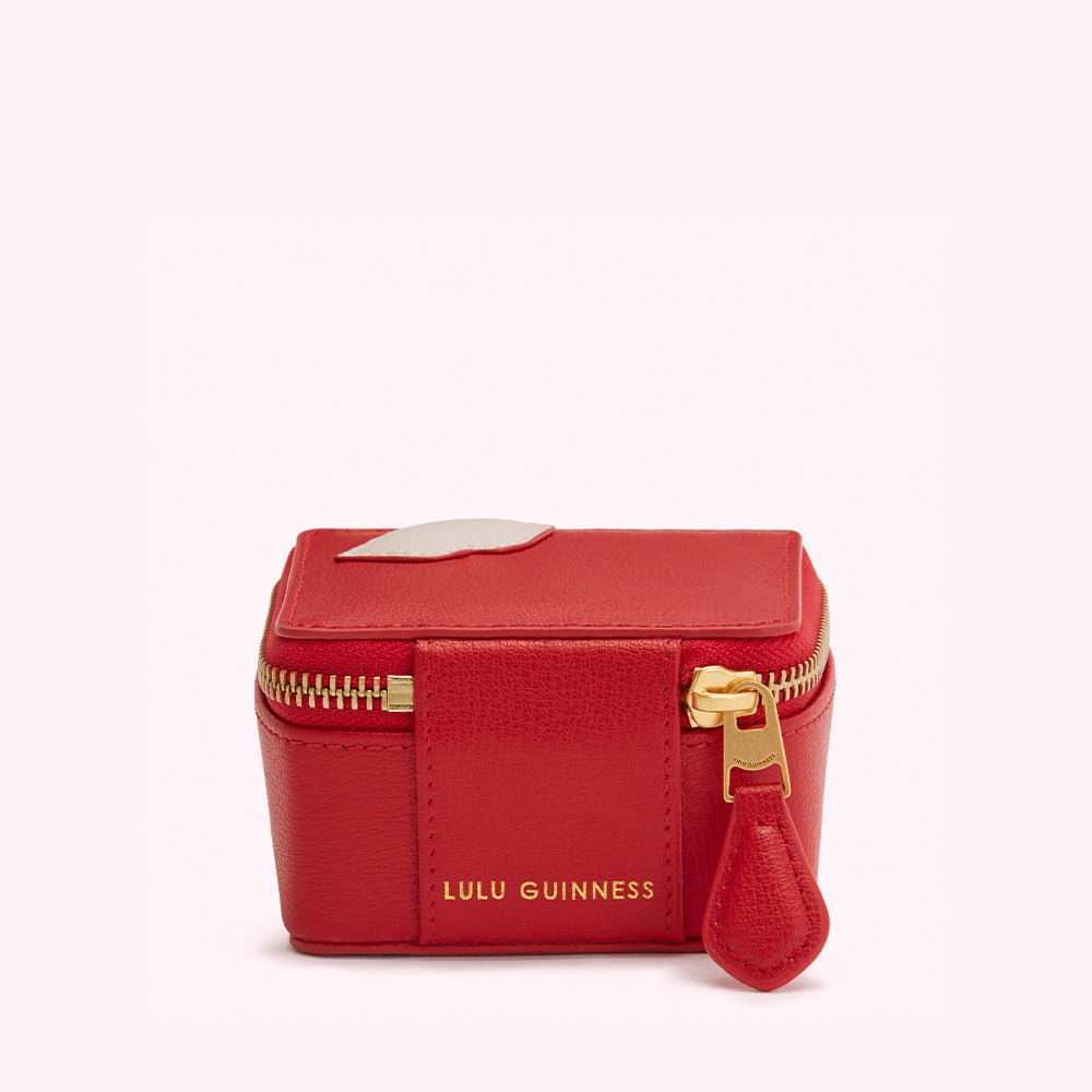 Red leather Lulu Guinness jewelry box with a white lip detail and gold zipper.
