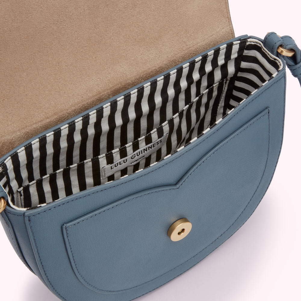 Interior view of a blue Lulu Guinness crossbody bag with black and white striped lining.
