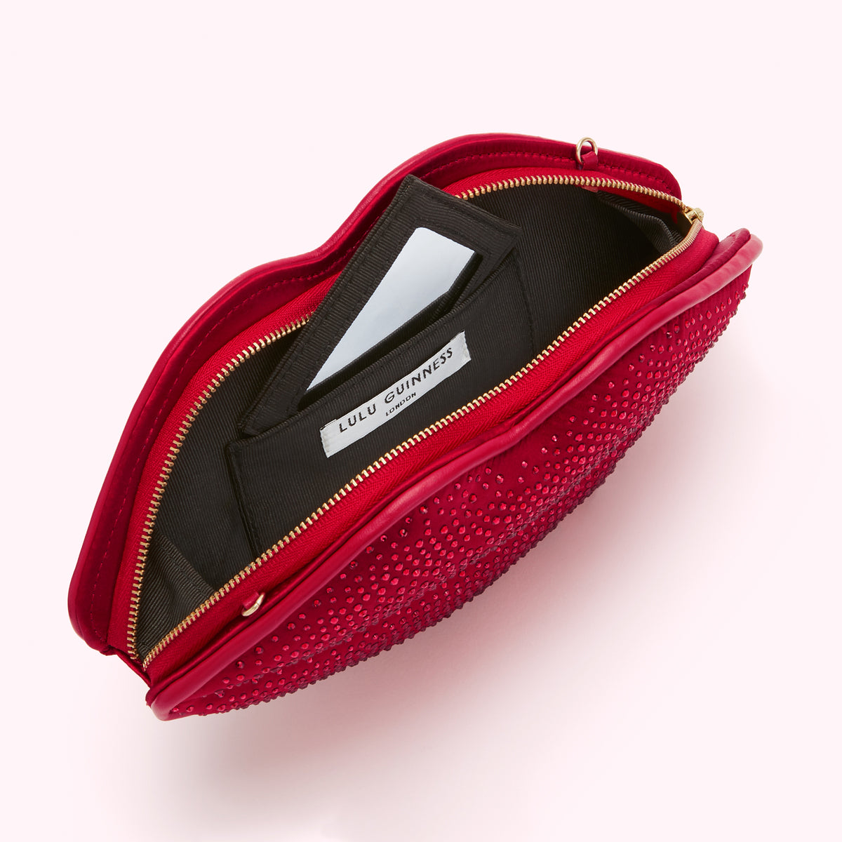 Red Lulu Guinness lip-shaped clutch open to reveal black interior and small mirror.