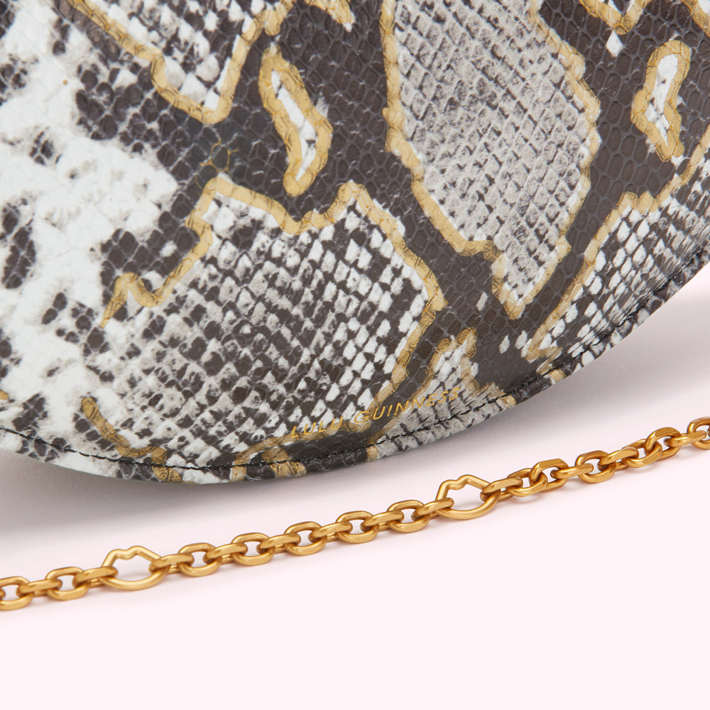Close-up of a Lulu Guinness handbag with a snakeskin pattern and gold chain strap.
