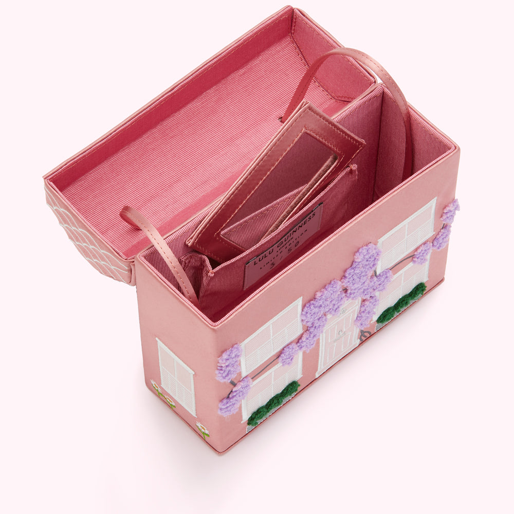Pink Lulu Guinness house-shaped box clutch bag open to reveal its interior and a small mirror.