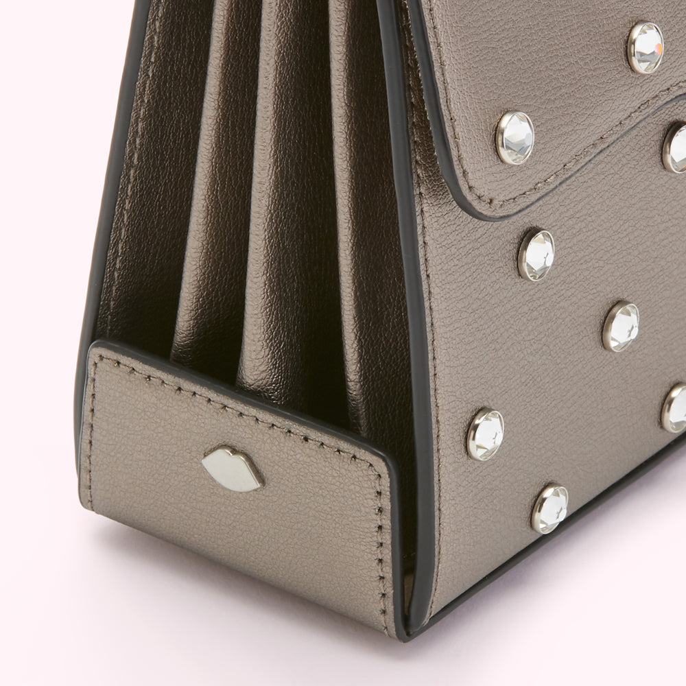 Close-up of a metallic gray handbag with crystal embellishments and a subtle lip logo.