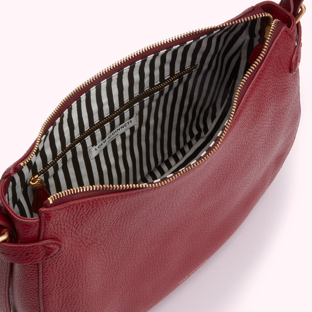 Red Lulu Guinness crossbody bag open to reveal black and white striped interior.