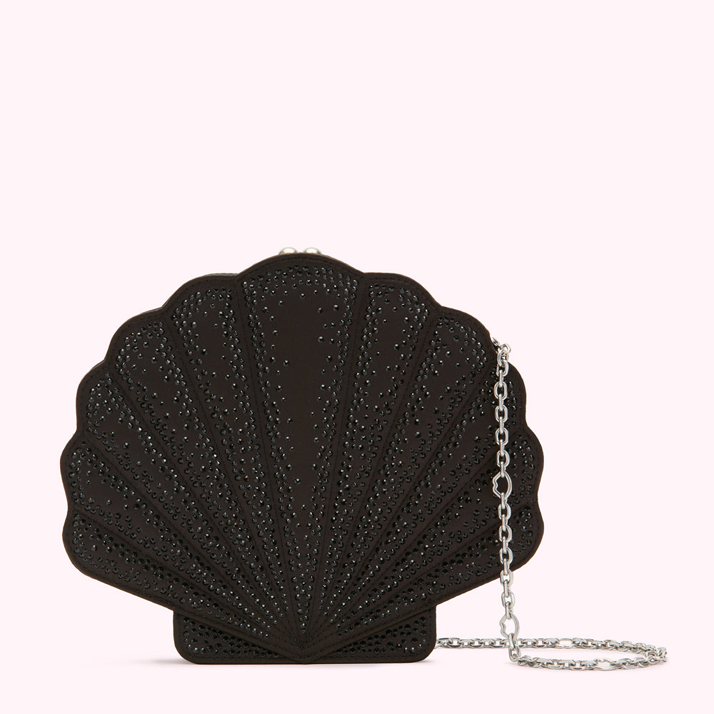 Black seashell-shaped clutch encrusted with black crystals and a silver chain strap against a white background.