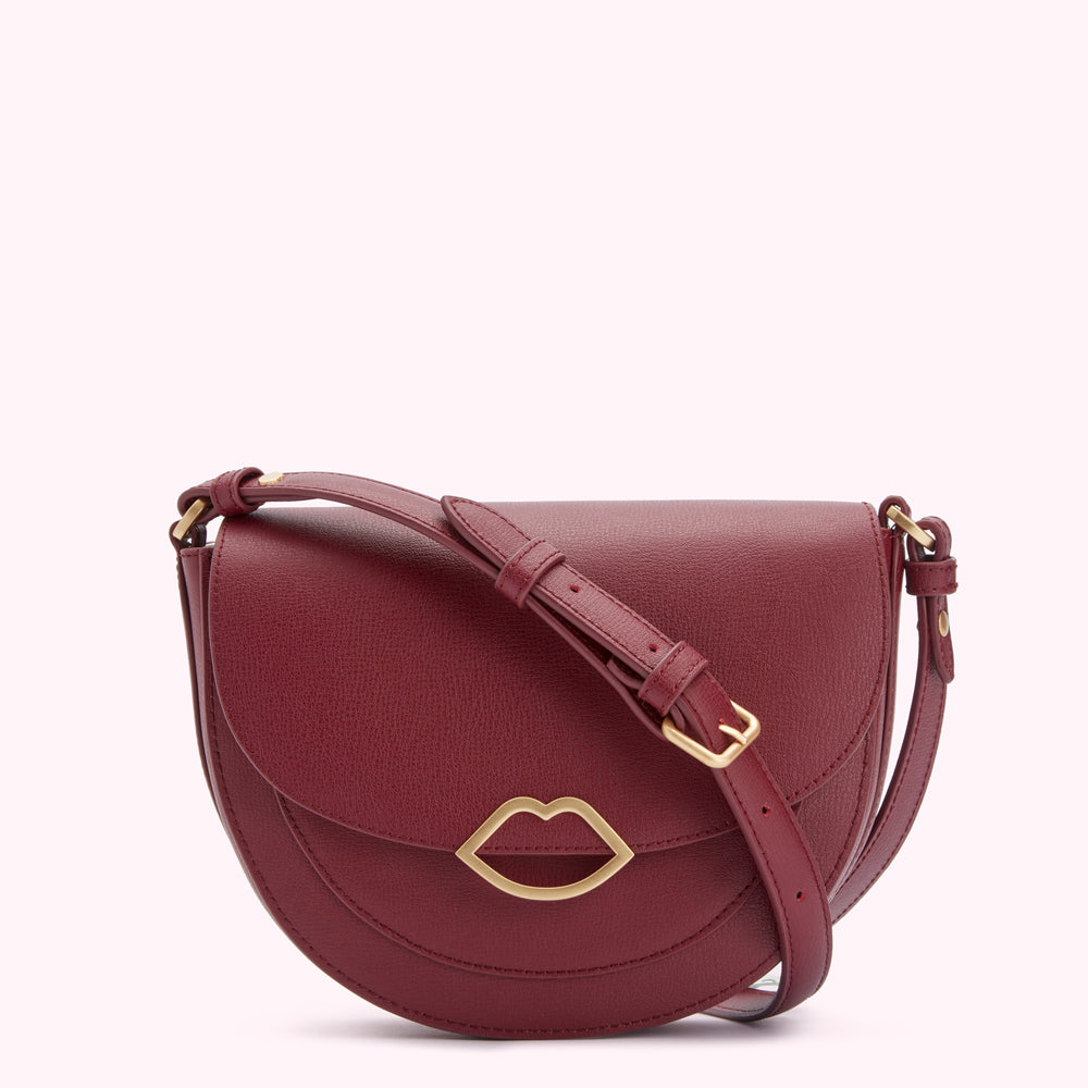 A burgundy half-moon crossbody bag with a gold lip-shaped clasp.
